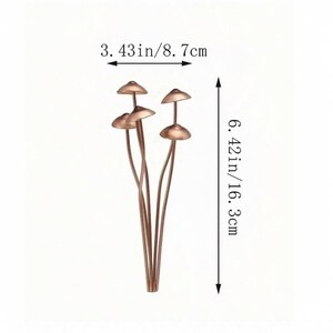 May include: A cluster of copper-colored mushroom-shaped decorative objects. The mushrooms are 3.43 inches wide (8.7 cm) and 6.42 inches tall (16.3 cm). The stems are thin and curved, and the caps are rounded and slightly flared.