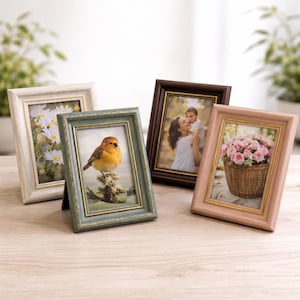 May include: Four decorative picture frames in various colors: white, teal, brown, and pink. Each frame holds a different image, including daisies, a bird, a mother and child, and a basket of roses. The frames are displayed on a wooden surface.