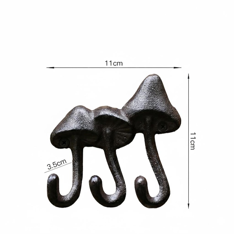 May include: A cast iron wall hook with three mushroom-shaped heads and curved hooks. The dark brown hook measures 11 cm in height and width, with the hooks extending 3.5 cm. The decorative hook is designed for hanging items.