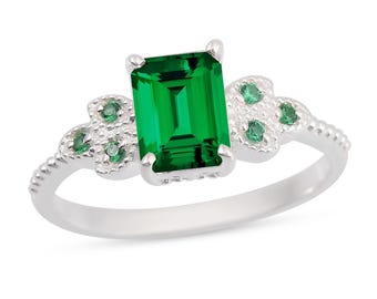 Puede incluir: Anillo de plata con una gran gema verde rectangular con talla esmeralda. El anillo tiene gemas verdes más pequeñas y diseños florales a ambos lados de la piedra principal. Una pieza de joyería.