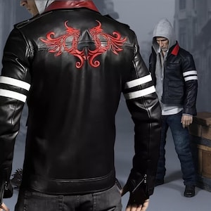 Könnte beinhalten: Schwarze Lederjacke mit rotem Stickmuster auf dem Rücken und weißen Streifen auf den Ärmeln. Die Jacke hat einen roten Kragen und einen Reißverschluss. Eine zweite Jacke ist im Hintergrund zu sehen.