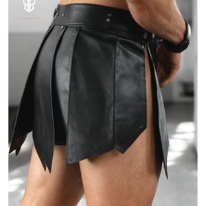 May include: Black leather skirt with a pleated design and a high waist. The skirt has a unique, asymmetrical cut with pointed edges. The garment is secured with a belt and rivets. The overall style is edgy and modern.