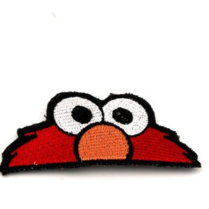 Può includere: Toppa ricamata raffigurante il volto di un personaggio rosso di Sesame Street con grandi occhi bianchi, pupille nere e naso arancione. La toppa ha un bordo nero, per abbigliamento o accessori.