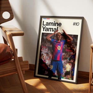 May include: Framed poster featuring a soccer player in a blue and red uniform, with the name "Lamine Yamal" and the number "10" displayed. The player is celebrating with arms raised. The poster is in a black frame.