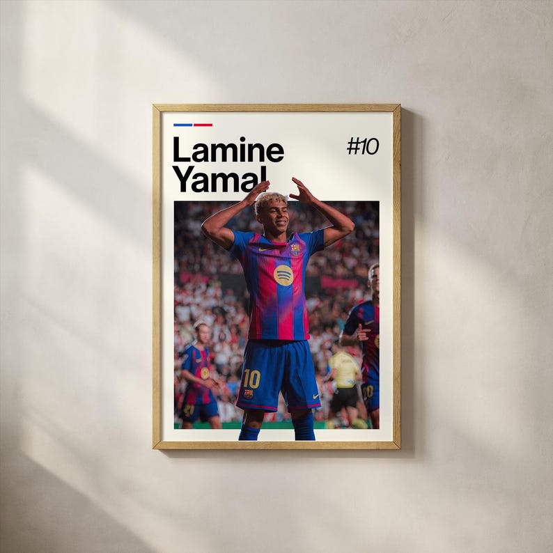 May include: A framed poster featuring a soccer player in a blue and red jersey, with the name "Lamine Yamal" and the number "10" displayed. The player is celebrating with arms raised. The poster has a wooden frame.