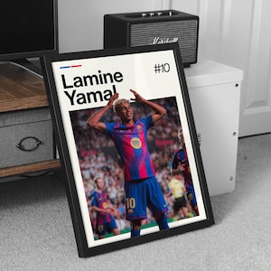 May include: Framed poster featuring a soccer player in a blue and red jersey with the number 10. The poster includes the player's name, "Lamine Yamal," and the number "#10" in the top right corner. The background shows a stadium filled with spectators.