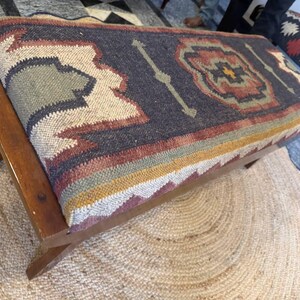 Close-up detail of tribal kilim upholstery on solid wood bench seat