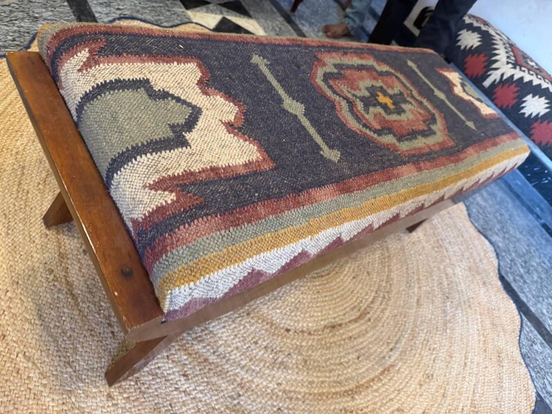 Close-up detail of tribal kilim upholstery on solid wood bench seat