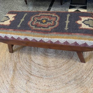 Close-up detail of tribal kilim upholstery on solid wood bench seat