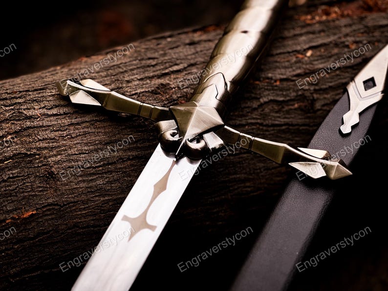 May include: A metallic sword featuring a polished blade with a central cutout design, a crossguard with pointed arms, and a textured handle. Beside the sword lies a black scabbard with a silver-toned metal tip, showcasing intricate geometric detailing.