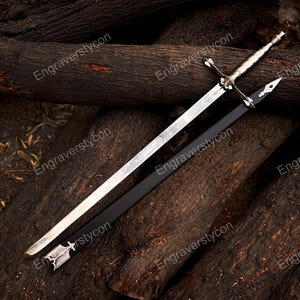 May include: A silver-toned metal sword with a cross-shaped guard and a textured handle, accompanied by a black scabbard featuring silver-colored metal accents at the tip and throat. The blade is straight, double-edged, and tapers to a sharp point.