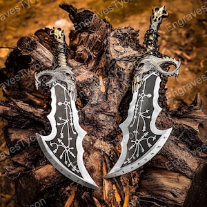 May include: Two silver and black fantasy blades with intricate designs and runes, resting on a weathered wooden surface. The blades have ornate handles and a skull-like design at the top. The blades are approximately 20 inches long.