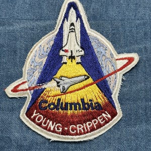 May include: Embroidered patch featuring the Space Shuttle Columbia launching. The patch has a white border, a blue and yellow background, and the words "Columbia YOUNG - GRIPPEN" in red and white.