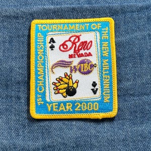 May include: A rectangular patch with a blue background and yellow border. The patch features text that reads "Tournament of Championship" and "Year 2000". The patch also has the text "Reno Nevada" and a bowling pin design.