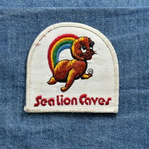 May include: A white ceramic mug with a black handle and the text "But First, Coffee" in a bold, black font. The mug is sitting on a wooden surface. The mug is approximately 4 inches tall.