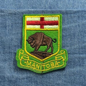 May include: A set of three ceramic mugs with a speckled, matte finish. The mugs are in shades of cream, light brown, and dark brown. Each mug has a simple, minimalist design and a rounded handle.