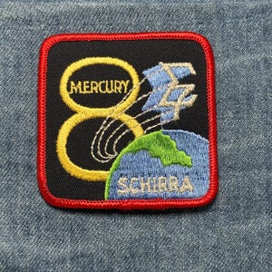 May include: A white ceramic mug with a black handle and the text "But First, Coffee" in a black, handwritten-style font. The mug is on a white surface.