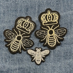 May include: Three embroidered bee patches. Two larger patches feature a bee design with a crown, and the smaller patch is a bee. The patches are black with gold and silver thread.
