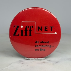 May include: A round, red button with the text "Ziff NET" in black and white. Below the logo, the button reads "All about computing... on-line". The button is sitting on a white surface.