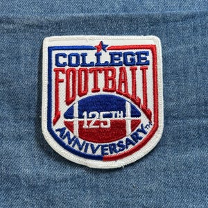 May include: A rectangular patch with a white border, featuring the words "COLLEGE FOOTBALL" in blue and red, and a football graphic. The text "125th ANNIVERSARY" is also present. The patch is set against a blue denim background.