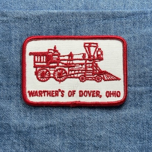 May include: A rectangular patch with a red border and a white center. The patch features a red illustration of a steam train. The text "Warthner's of Dover, Ohio" is printed in red below the train illustration.