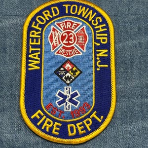 May include: A blue and yellow embroidered patch for the Waterford Township Fire Dept. The patch features the words "Waterford Township, N.J." and "Fire Dept." along with a fire department emblem and the year "Est. 1998".