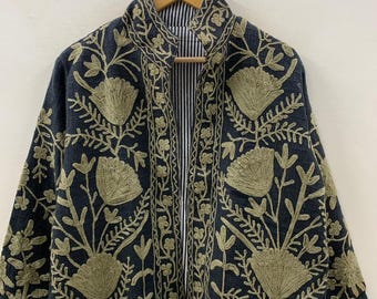 Pode incluir: Casaco cinza escuro com intrincados bordados florais dourados. O casaco apresenta uma gola alta e um forro listrado visível na abertura frontal. O bordado inclui padrões detalhados de flores e folhas, criando um design texturizado e ornamentado.