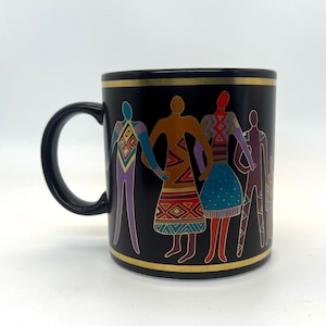 Puede incluir: Taza de cerámica negra con borde y asa dorados. La taza presenta un diseño colorido de figuras estilizadas tomadas de la mano. Las figuras son en tonos morado, marrón, rojo y azul, con patrones geométricos.