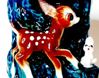 May include: A ceramic planter with a blue and green glaze features a brown and white deer with white spots and a white rabbit. The deer is running and the rabbit is sitting.
