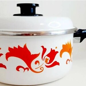 May include: White enamel pot with a black handle and lid. The pot has a floral design in orange and red.