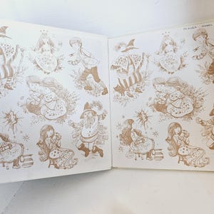 Puede incluir: Libro abierto con ilustraciones en tonos sepia. Los dibujos representan una bruja, un ni&ntilde;o, una ni&ntilde;a y un gnomo. Las ilustraciones son detalladas y caprichosas, con una est&eacute;tica vintage. El libro est&aacute; abierto, mostrando la obra de arte en dos p&aacute;ginas.