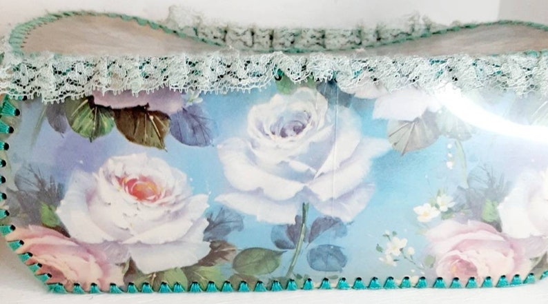 May include: A blue and white floral patterned box with a lace trim and a green scalloped edge.
