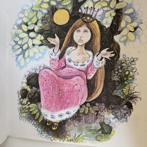 Puede incluir: Ilustraci&oacute;n de una princesa con largo cabello casta&ntilde;o, vestida con un vestido rosa con ribetes blancos y una corona. Est&aacute; sentada en un &aacute;rbol con tronco y ramas oscuras, rodeada de hojas y un estanque con una rana.