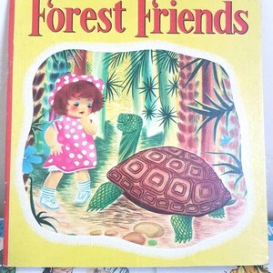 Puede incluir: Un libro infantil vintage titulado "Forest Friends" con una portada amarilla y una ilustración colorida de una niña con un vestido de lunares rojos y blancos mirando a una gran tortuga verde y marrón en un entorno de bosque.