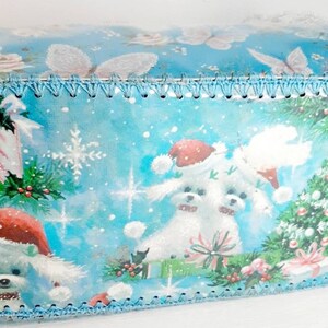 Pu&ograve; includere: Carta da regalo natalizia blu e bianca con un design di due cani bianchi con cappelli da Babbo Natale, un albero di Natale e bastoncini di zucchero. La carta ha un bordo di uncinetto blu attorno ai bordi.