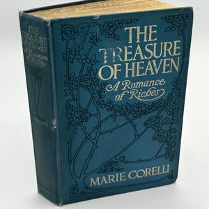 May include: A vintage hardcover book titled "The Treasure of Heaven" by Marie Corelli. The book has a teal cover with gold lettering and floral designs. The edges of the pages are gold. The book is in good condition.