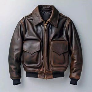 Puede incluir: Chaqueta bomber de cuero marrón con cremallera, dos bolsillos delanteros y cuello. La chaqueta tiene puños y cintura de canalé negros. El cuero tiene un aspecto envejecido.