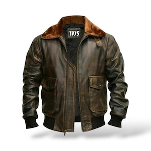 May include: A brown leather bomber jacket with a fur collar. The jacket features two front pockets, a zip closure, and black ribbed cuffs and hem. The collar has the text "TVS".