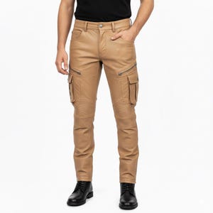 May include: Tan leather trousers with cargo pockets and ribbed knee panels. The trousers have zipped pockets and a button closure. The model is wearing black boots.
