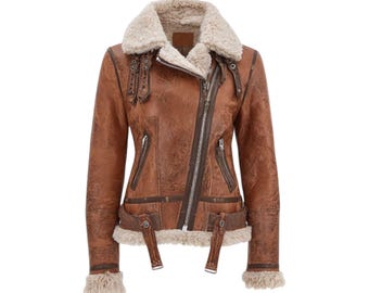 May include: Brown leather jacket with a cream-colored shearling collar and lining. The jacket features a diagonal zipper, multiple pockets, and decorative straps. The jacket has a distressed finish and a classic aviator style.