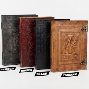 May include: Four leather journals in charcoal, brown, black, and tobacco shades. Each journal has an embossed tree design and a metal clasp. The journals are upright, highlighting their intricate details and varied colours.