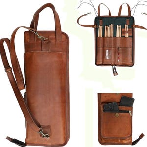 May include: A brown leather drumstick bag with a shoulder strap and a top handle. The bag has multiple pockets and compartments for drumsticks and accessories. The bag is made of a durable leather material and has a vintage look.