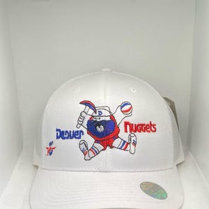 May include: White baseball cap featuring the Denver Nuggets mascot in red, white, and blue embroidery. The cap has a mesh back and a curved brim. The words "Denver" and "Nuggets" are embroidered on the cap.