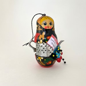 Peut inclure: Une infuseur à thé peint en noir et rouge en forme de poupée gigogne russe avec une passoire en métal et une étiquette qui dit "Imma Teapot".