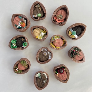 May include: Twelve walnut shells, each with a unique design and a small face inside. The shells are decorated with beads, flowers, and other embellishments.