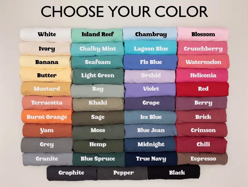 Puede incluir: Una exhibici&oacute;n de camisetas dobladas en varios colores, incluyendo blanco, azul, rosa y negro. El texto "CHOOSE YOUR COLOR" est&aacute; en la parte superior, con nombres de colores como "Blossom", "Chili" y "True Navy" etiquetando cada pila. Las camisetas est&aacute;n bien ordenadas.
