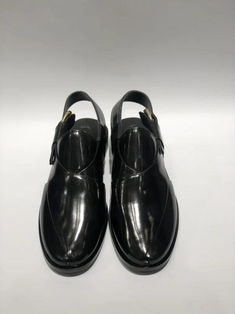 May include: Pair of black leather sandals with a glossy finish. The sandals have a slingback design with a buckle closure and a rounded toe. The soles are black and the sandals appear to be unworn.
