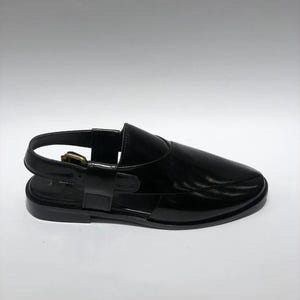 May include: Black leather sandal with a slingback strap and buckle closure. The sandal features a rounded toe and a flat sole. The shoe has a glossy finish and a minimalist design.