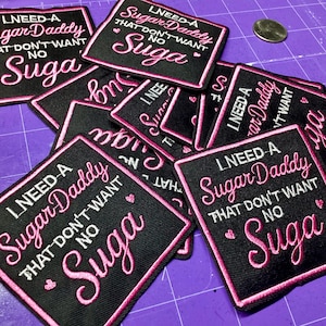 May include: Black embroidered patches with pink and white text that reads "I NEED A Sugar Daddy THAT DON'T WANT NO Suga". The patches have a pink border and small heart details.