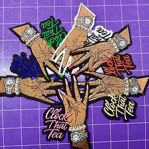 May include: Embroidered patches featuring stylized hands with long, painted nails and pearl-studded wristwatches. Each patch has the phrase "Clock That Tea" in a different color. The patches are arranged on a purple surface.